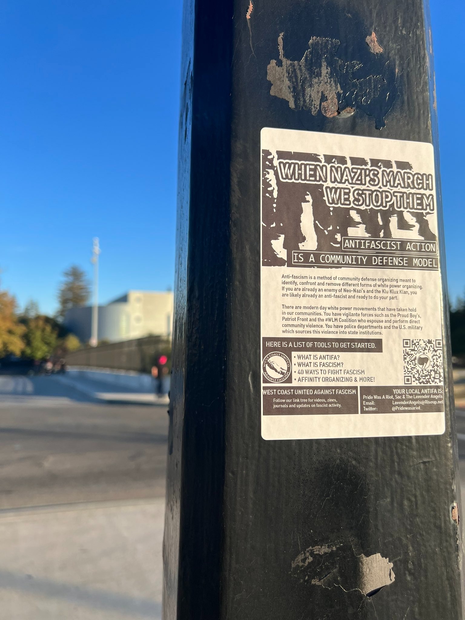 A flyer reads "when Nazis march we stop them. Antifascist action as community defense model." In the distance is a bridge.